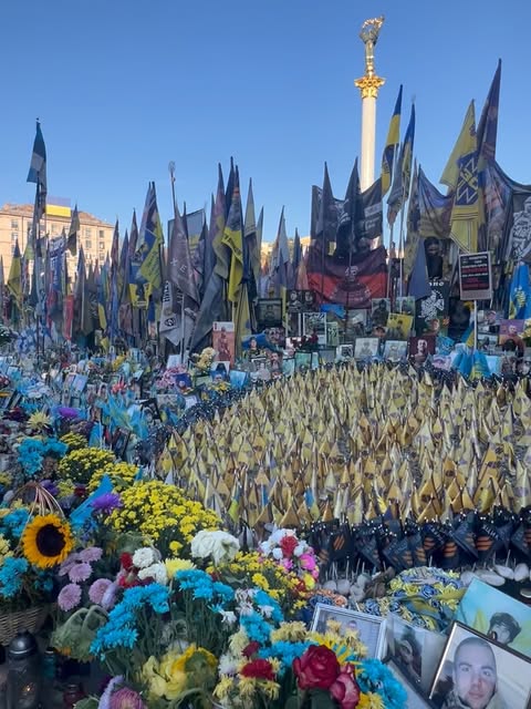 Flowers, portrait photographs and rows of Ukrainian flags beneath the Independence Monument in Kyiv.